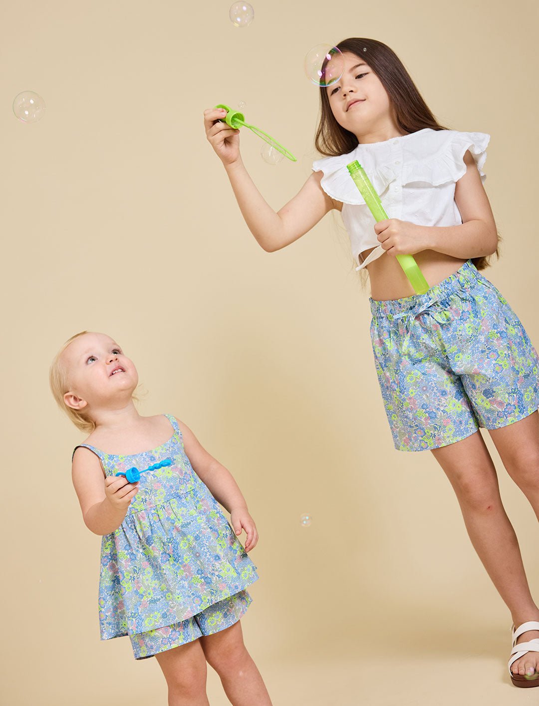 Two girls blowing bubbles wearing the Delilah liberty print range - ce-jour la