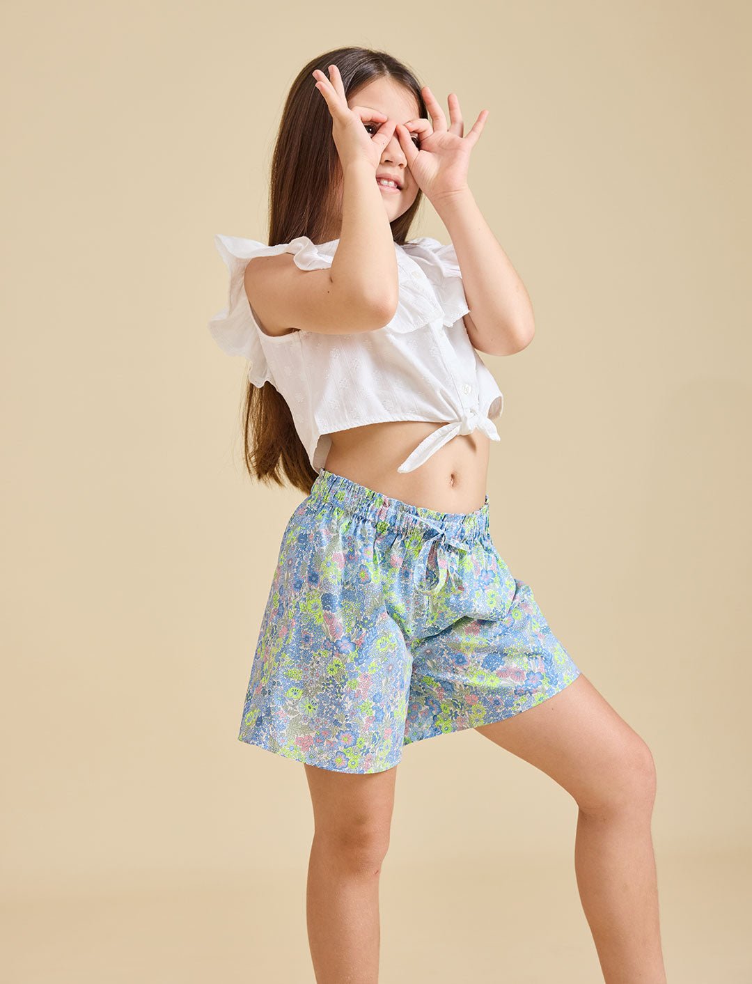 Girl modelling the delilah liberty print shorts with a beige background - ce-jour la