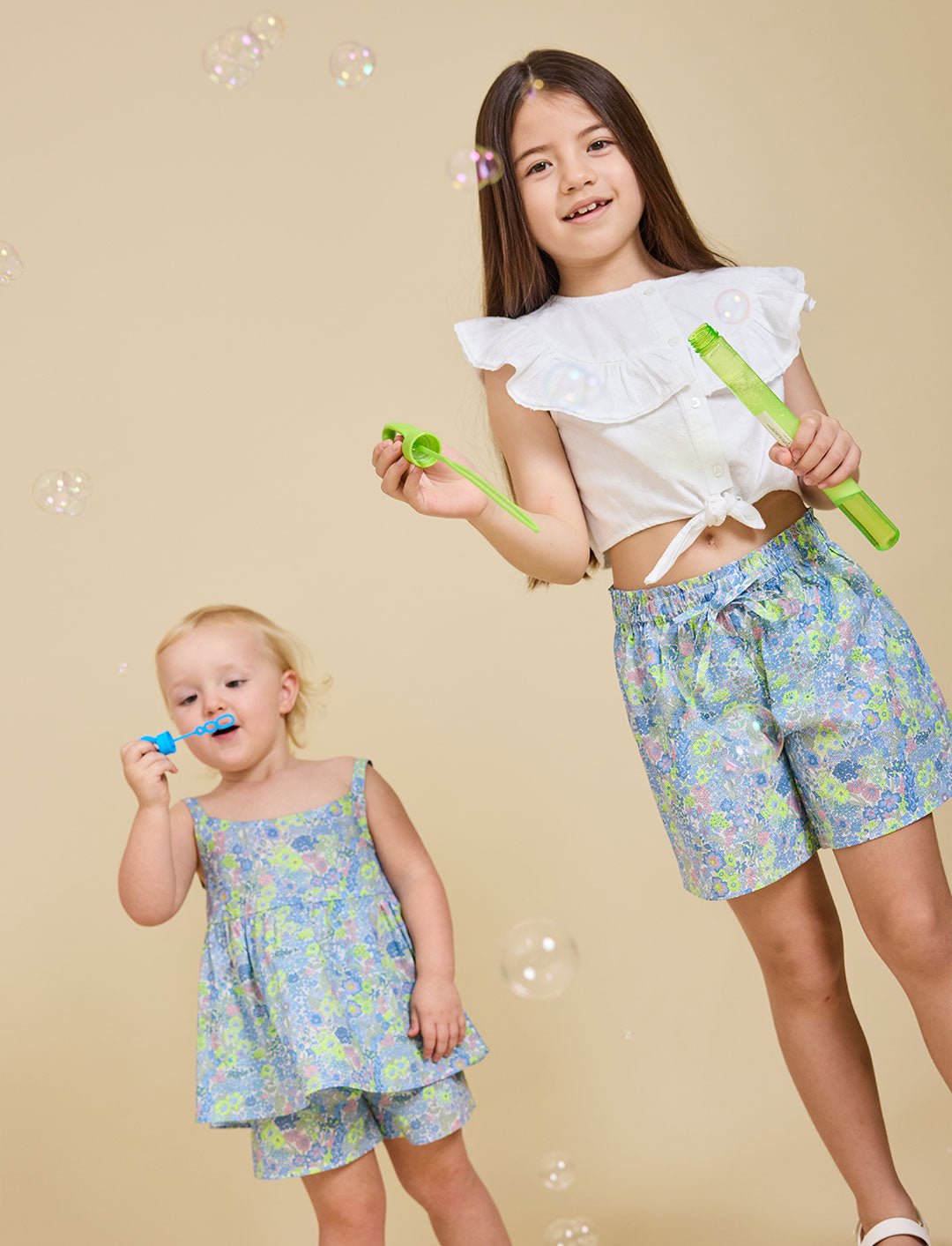 Two girls blowing bubbles wearing the Delilah liberty print range - ce-jour la