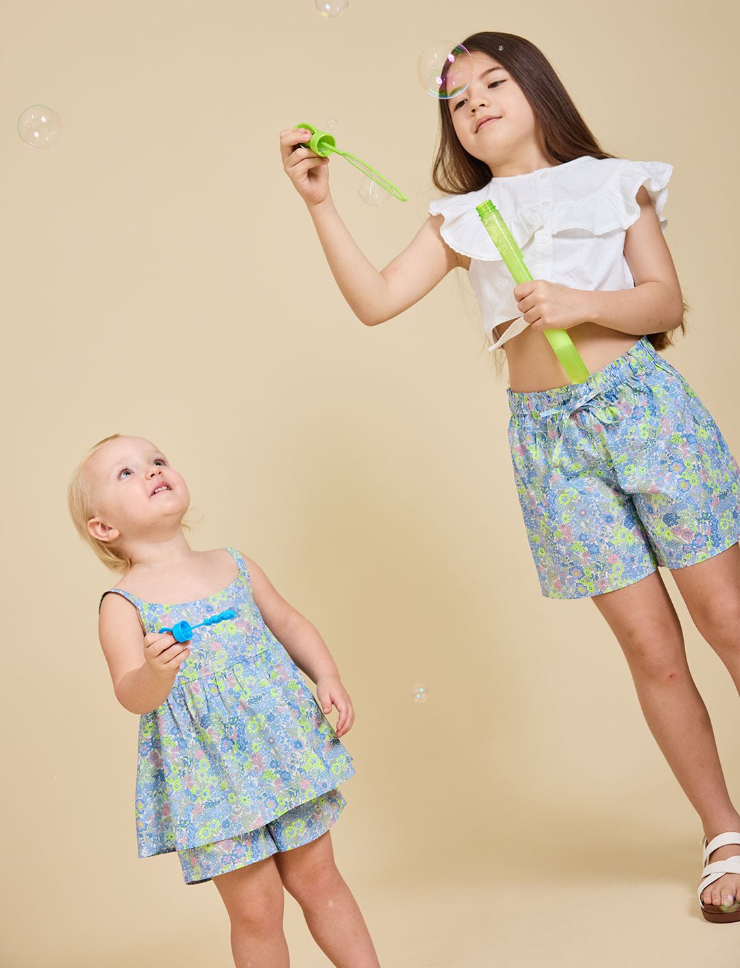 Two girls blowing bubbles wearing the Delilah liberty print range - ce-jour la