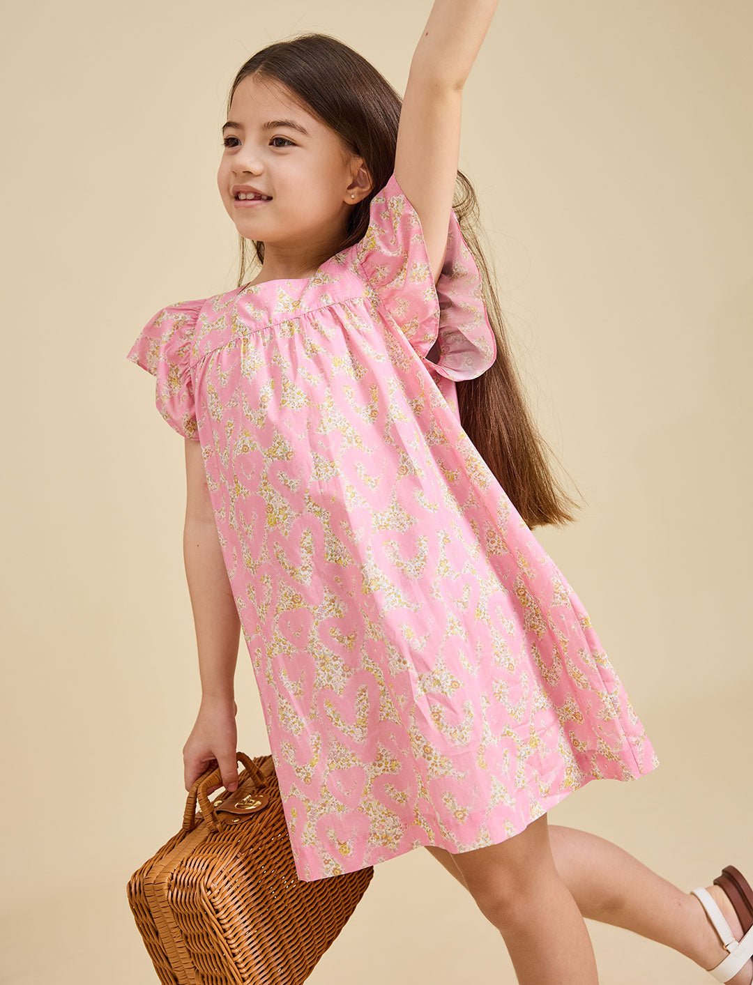 Girl on a beige background wearing the Margaux dress in pink