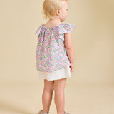 A girl with a beige background modelling a flowery top