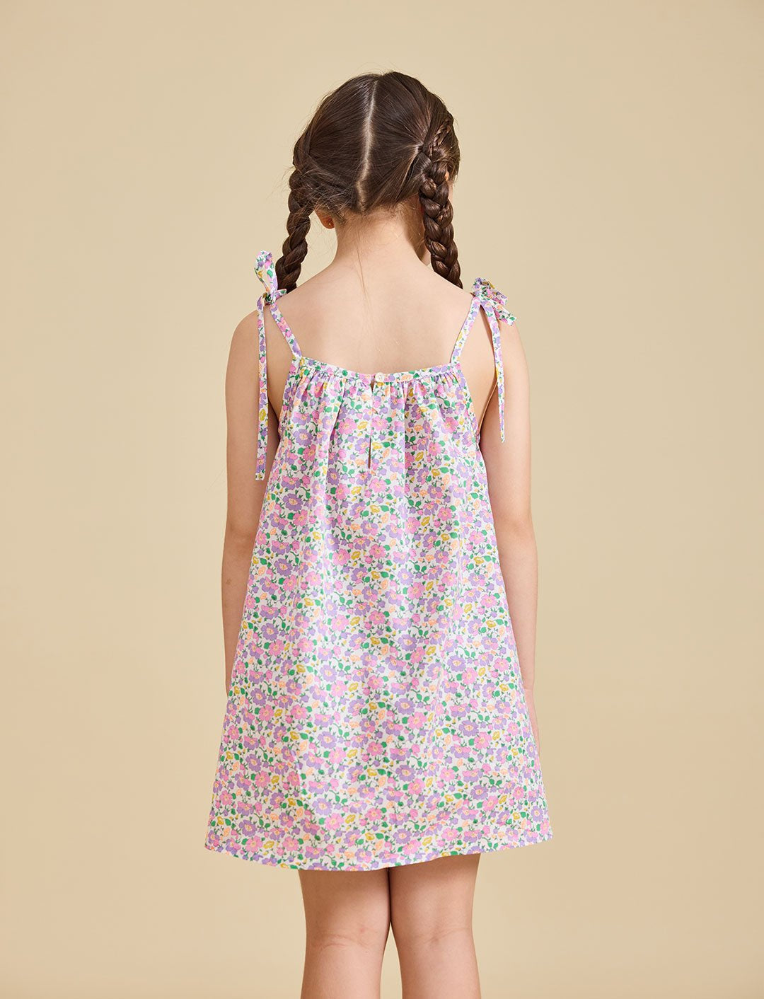 Back view of girl wearing the fleur dress with beige background 